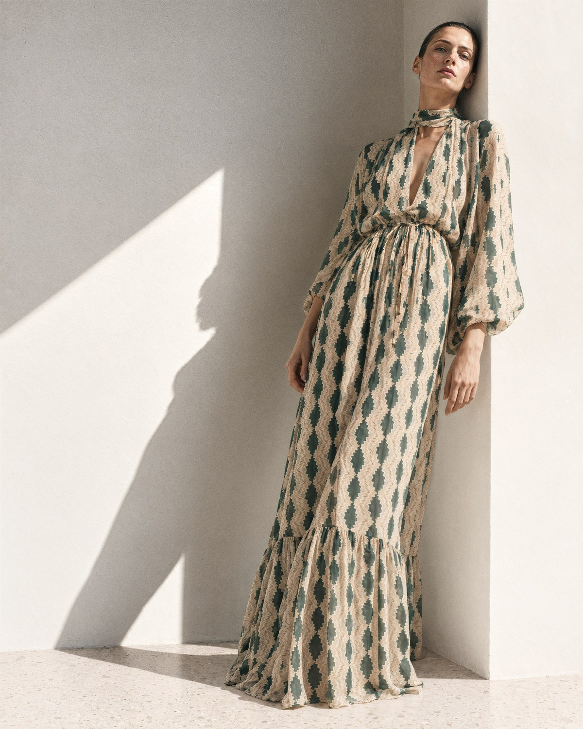 The Theo dress in Lazzar print, leaning in the corner of a sunlit white room