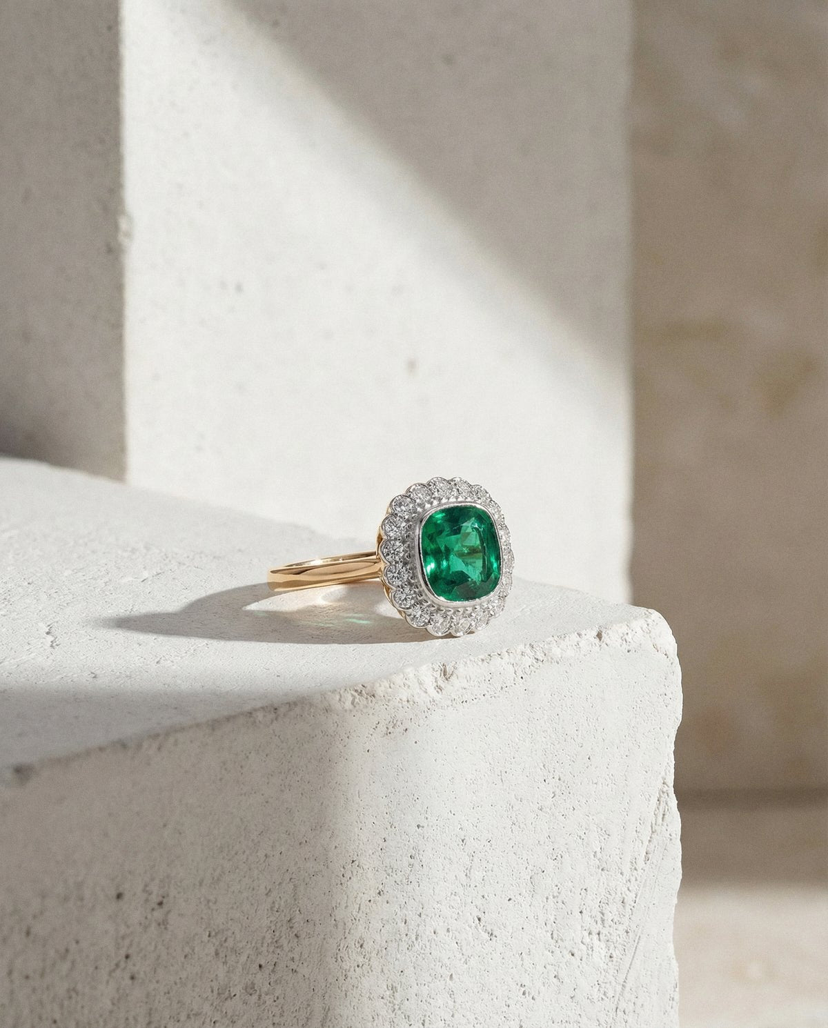 ICON 02, an emerald and diamond ring resting on a stone block in sunlight
